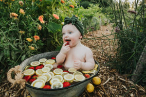 Chewing on strawberry and lemon fruit bath to celebrate Evie's first birthday in Hillsboro, Oregon.
