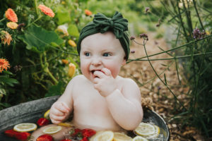 Chewing on strawberry and lemon fruit bath to celebrate Evie's first birthday in Hillsboro, Oregon.