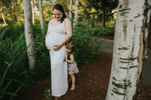 Pregnant mom savors a hug from her oldest daughter thinking about pregnancy the second time around in Hillsboro, Oregon
