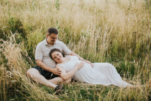 Dad/Partner looks on with affection at his wife who is pregnant the second time around in some tall grass in Hillsboro, Oregon.