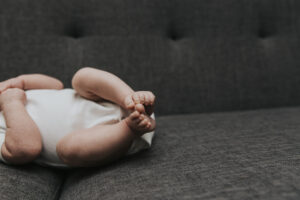 Close up of baby toes on a gray couch at a lifestyle newborn session by Portland Newborn photographer.