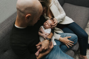 Mom cradles baby's head while Dad holds her during lifestyle newborn session by Portland Newborn Photographer.