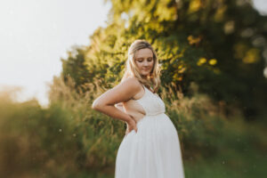 Pregnant mom holds her hands on her back with her eyes closed and dust particles flying around during her maternity session in Yamhill, Oregon
