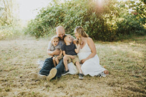 A family with pregnant mom, dad, and 2 little boys snuggle on a blanket in Yamhill, Oregon