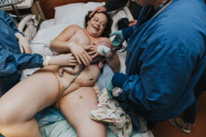 Birthing mom is laying down with a huge smile on her face as her newborn baby is laid onto her chest after a long delivery at Kaiser Westside in Hillsboro Oregon